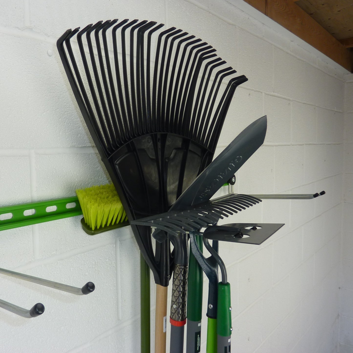 garden tool storage with a hook holding 6 tools including a broom, leaf rake, trenching spade, rake, large and small hoes