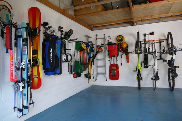 Inside of a garage with wall mounted storage racks showing how bikes, sports equipment and garden tools can be stored on wall mounted racks