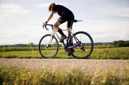 Cyclist riding road bike on countryside gravel path during outdoor training