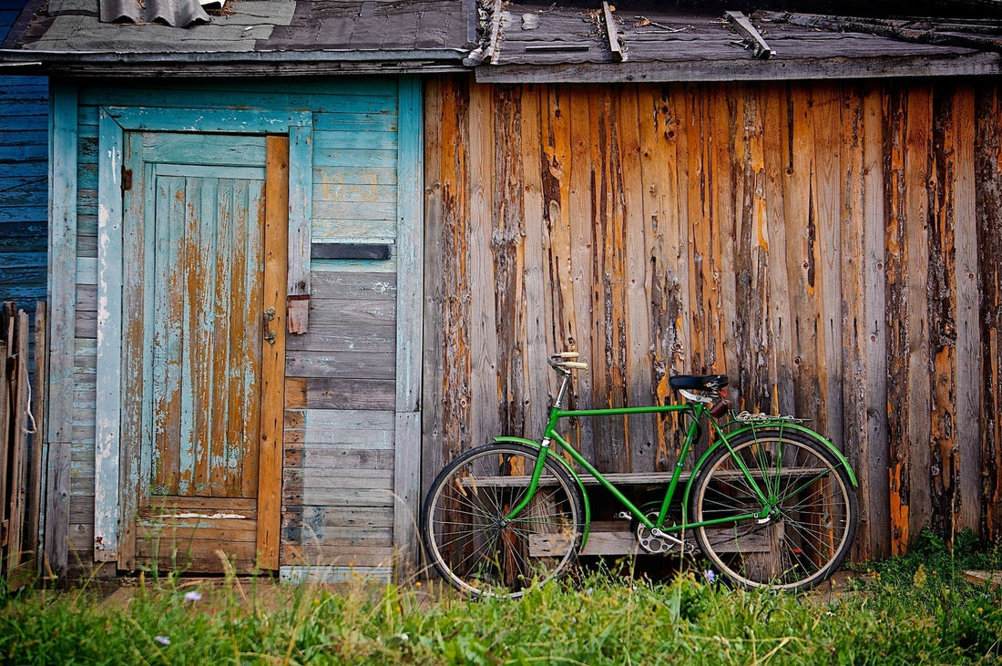 A green bike next to a wooden shed