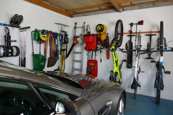 Inside of a garage with wall mounted storage racks showing how bikes, sports equipment and garden tools can be stored on wall mounted racks and leave space for a car