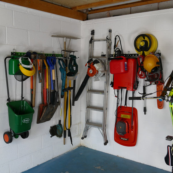 Garden tool rack for sheds and garages . Inside of a garage with wall mounted garden tool racks showing how bikes, sports equipment and garden tools can be stored on wall mounted racks