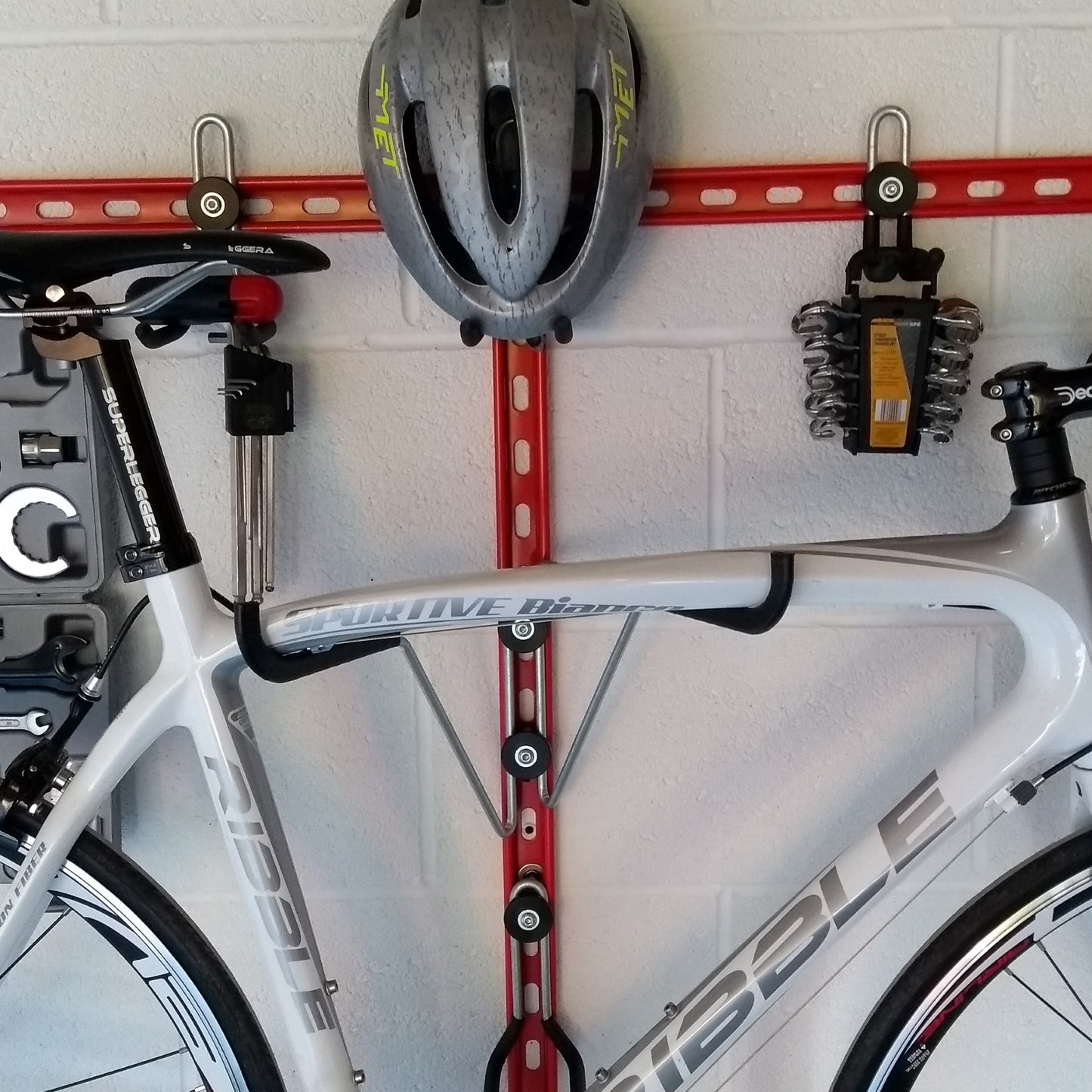 Horizontal folding bike hooks, work stand and double gear storage.. Close up of a Horizontal bike rack, wall mounted bike storage with a road bike, helmet and tools