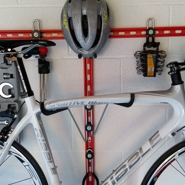 Horizontal folding bike hooks, work stand and double gear storage.. Close up of a Horizontal bike rack, wall mounted bike storage with a road bike, helmet and tools