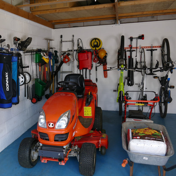 Garden tool rack for sheds and garages. Inside of a garage with wall mounted garden tool racks showing how bikes, sports equipment and garden tools can be stored on wall mounted garden tool rack