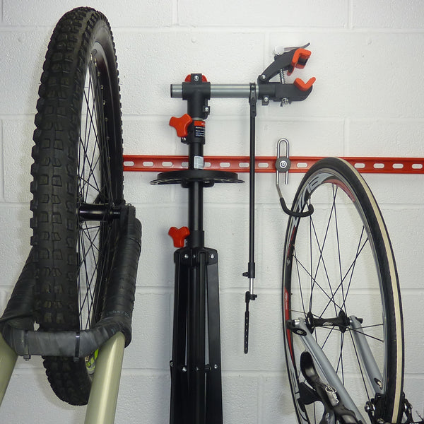Bike wall rack for 3, 4 or 5 bikes with storage hook for a maintenance work stand mounted between the bikes on a GearRail.