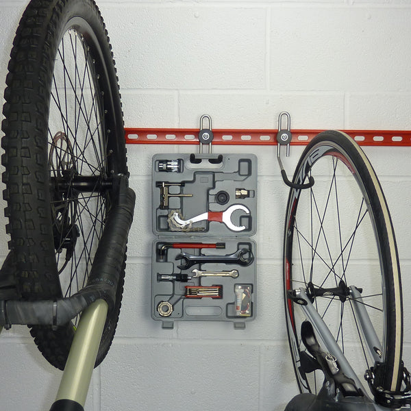 Wall bike rack with an extra storage hook for a tool kit mounted between the bikes